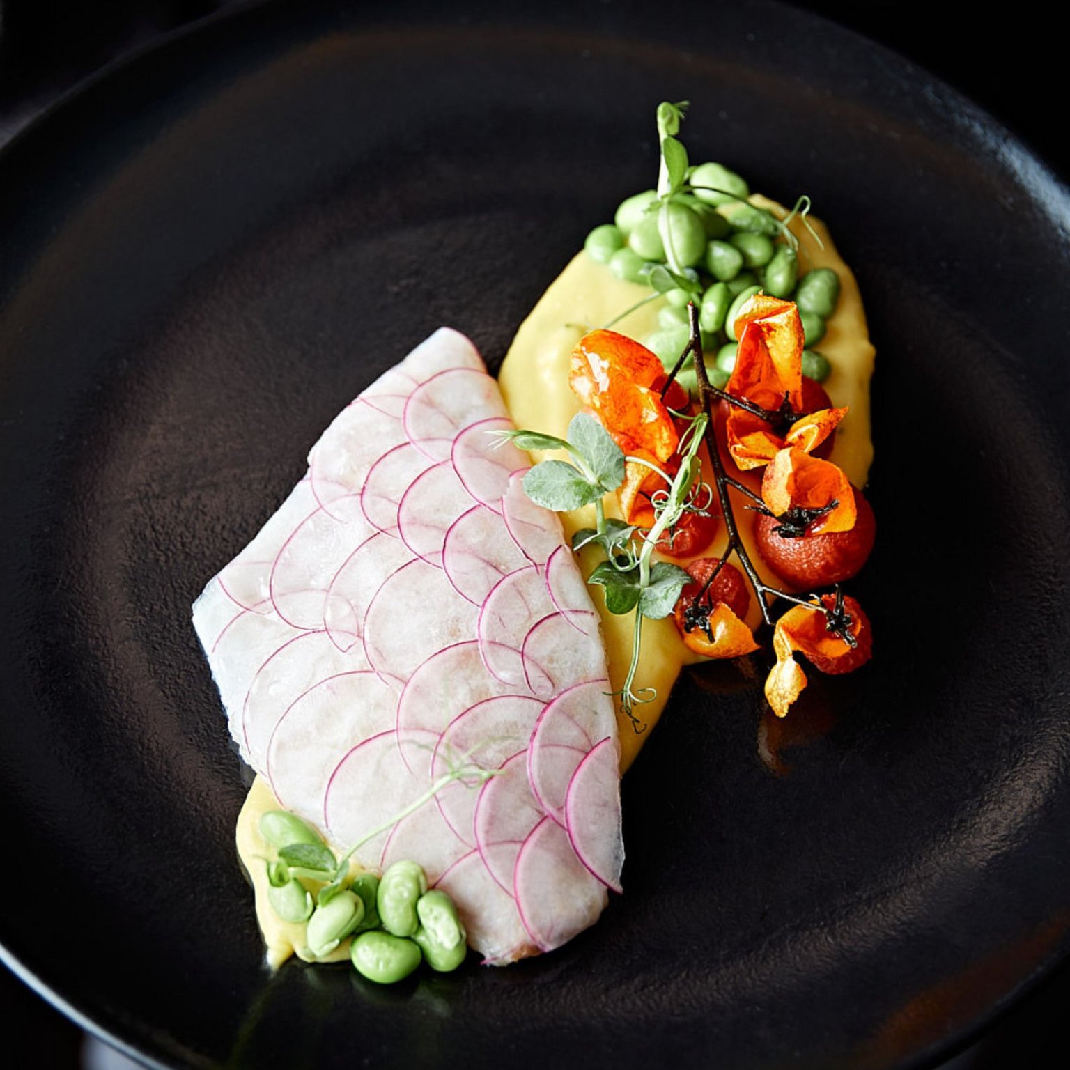 Vacanze in Tirolo all’insegna del gusto Piatto elegante con fette sottili di ravanello, piselli e verdure su piatto nero