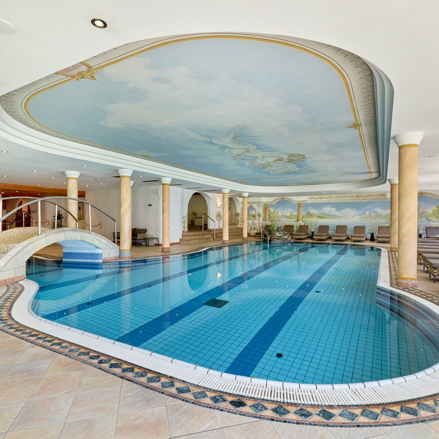 Ab ins Wellnesshotel im Stubaital! Innenpool mit Bogenbrücke und dekorativer Decke in einem Wellnessbereich