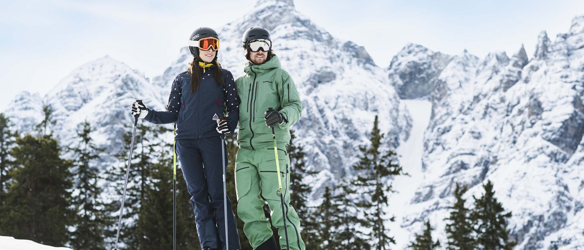 Die Weihnachtszeit bei uns Paar in Skiausrüstung vor verschneiter Berglandschaft und Tannenbäumen