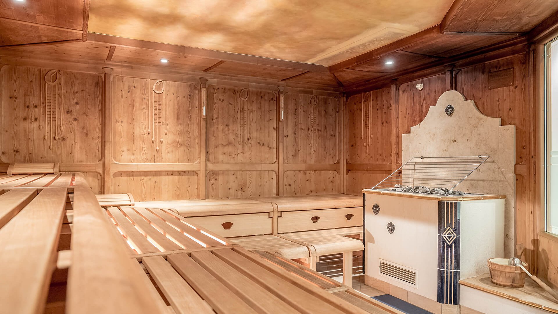 Stubaital: our hotel with a pool Bright wooden sauna interior with stove and water ladle