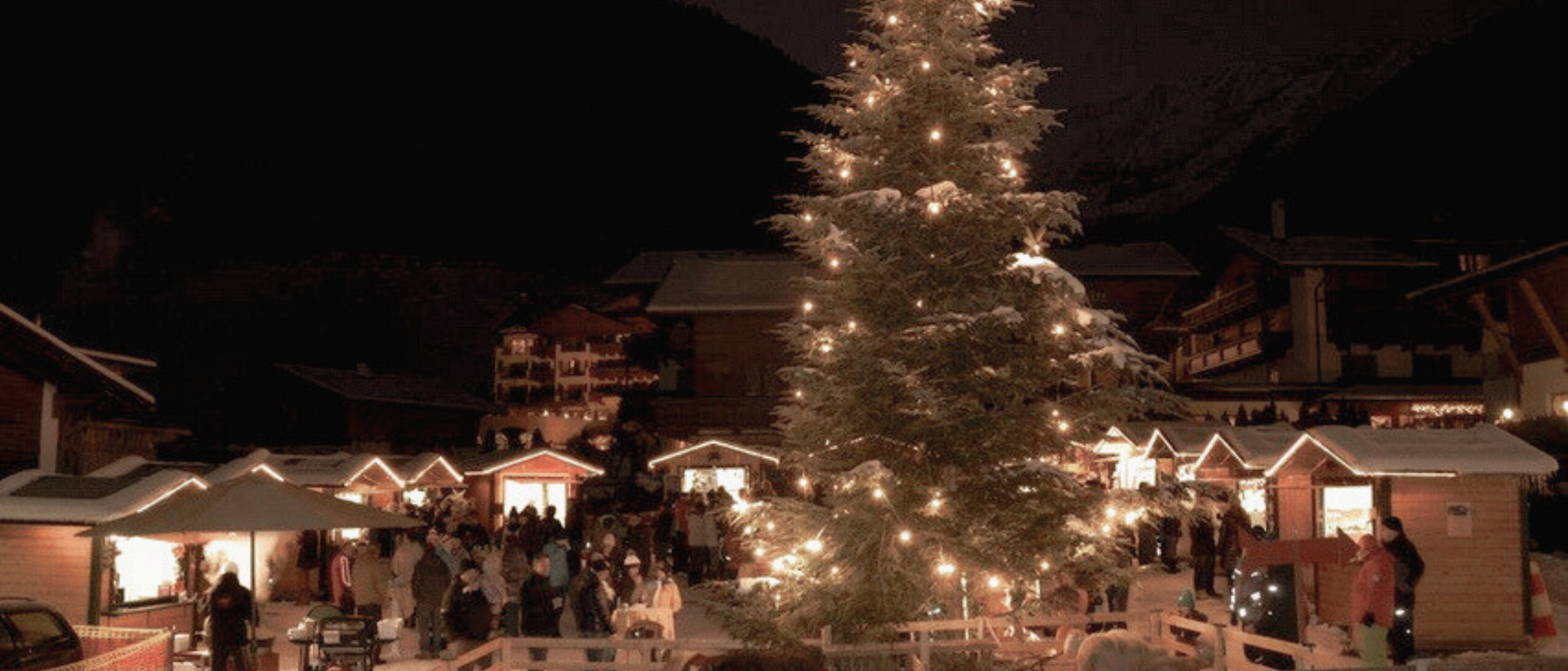 Die schönsten Christkindlmärkte in der Umgebung Beleuchteter Weihnachtsbaum auf einem verschneiten Weihnachtsmarkt bei Nacht
