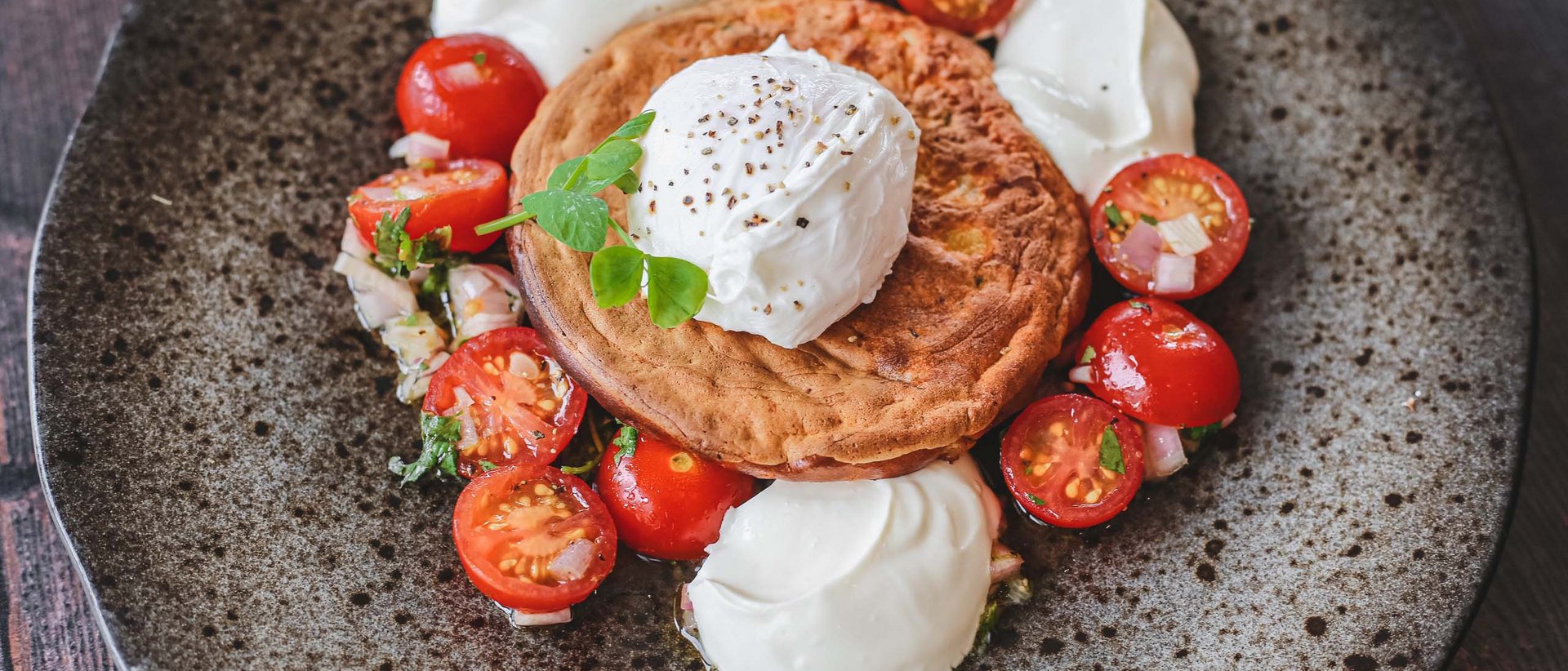 Eine kulinarische Reise durch die Tiroler Bergwelt Pochiertes Ei auf Brot mit Kirschtomaten und Sahne auf einem Teller
