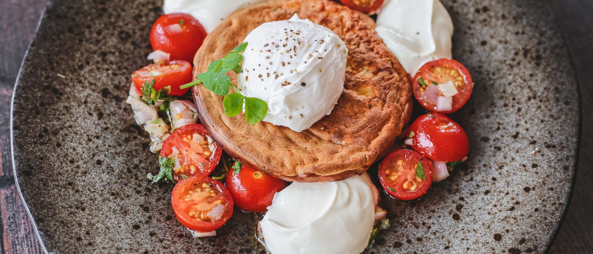 Eine kulinarische Reise durch die Tiroler Bergwelt Pochiertes Ei auf Brot mit Kirschtomaten und Sahne auf einem Teller