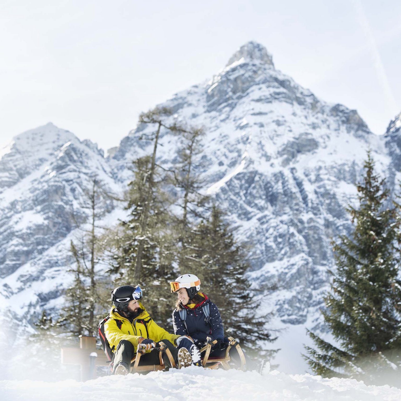 Lo sci di fondo in Austria è imperdibile Coppia su slittino con montagne innevate e pini sullo sfondo