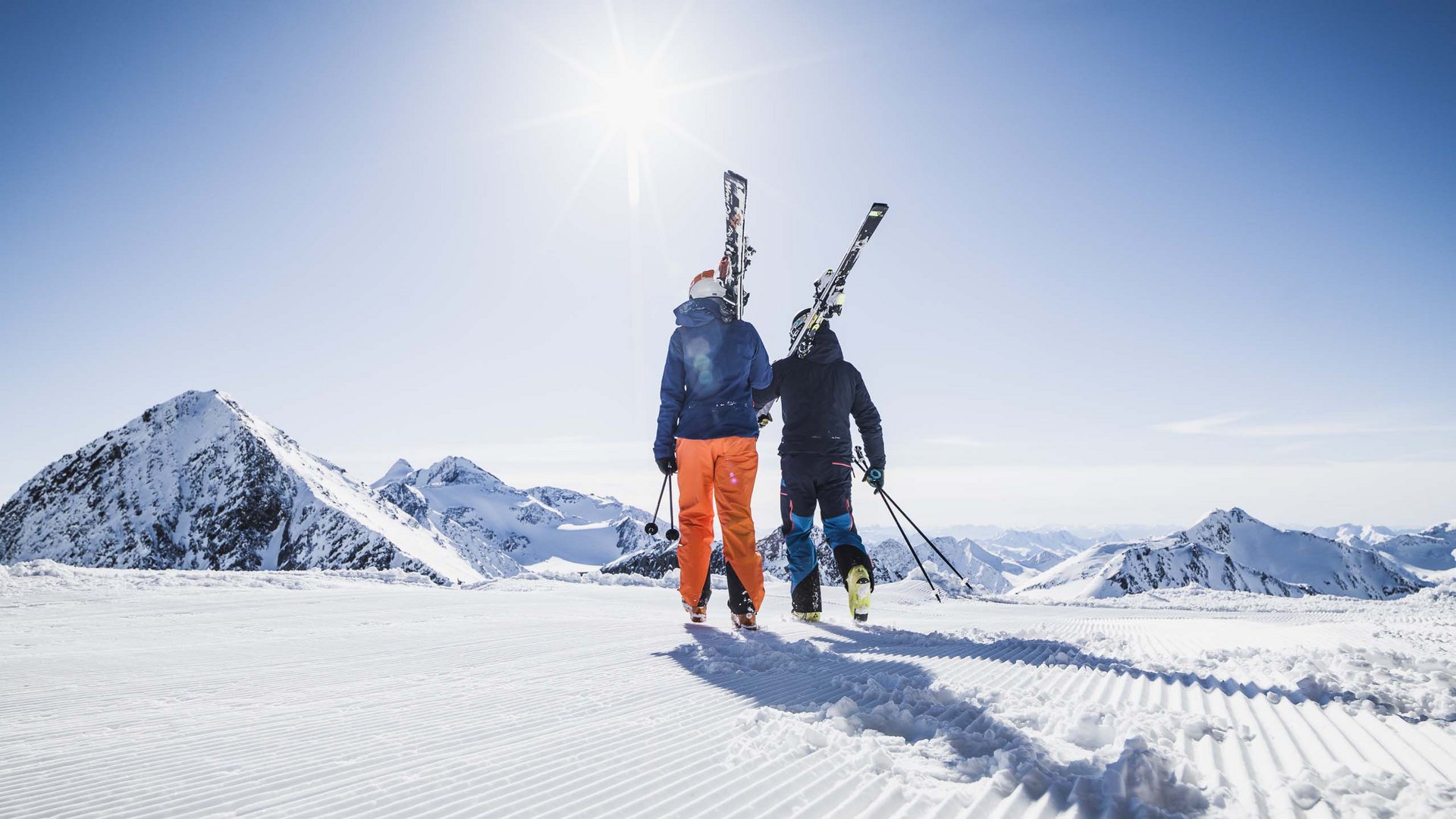 Der Stubaier Gletscher Zwei Skifahrer tragen Skier bei sonnigem Wetter auf frisch präparierter Piste