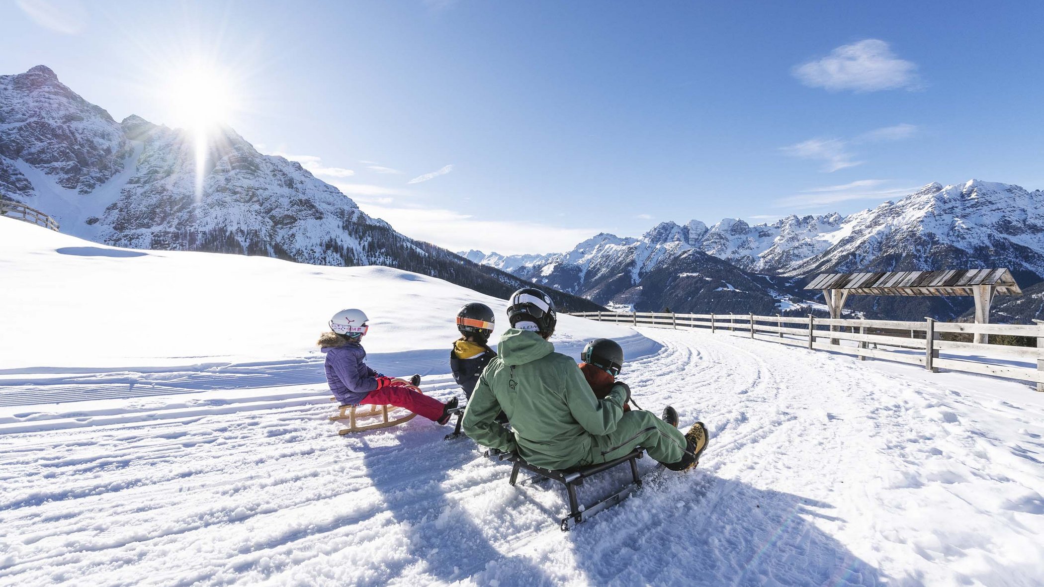 In Stubaital ci son mille cose da fare Persone che fanno slittino su strada innevata in paesaggio montano soleggiato