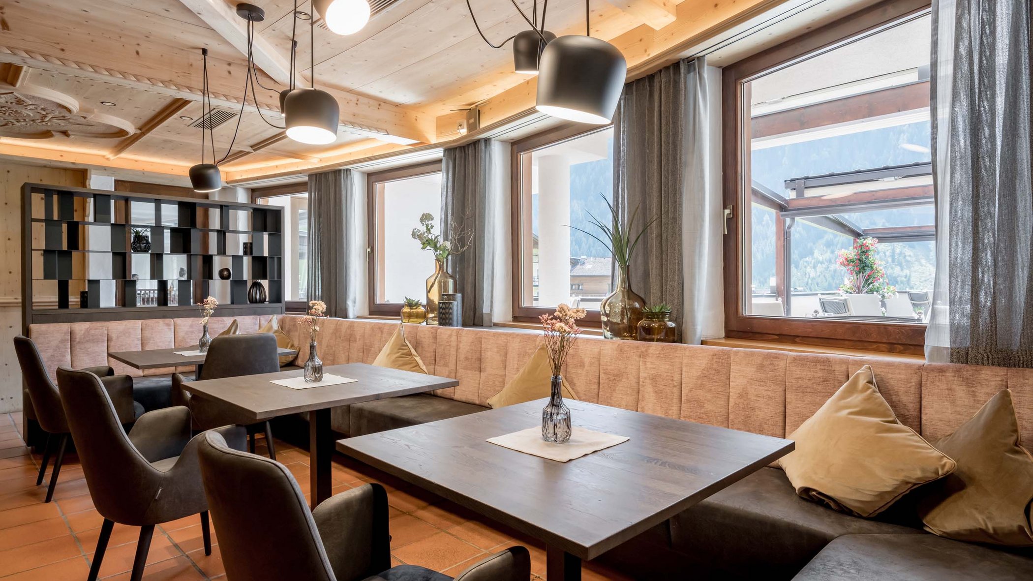 Off to the wellness hotel in Stubaital! Cozy dining area with wooden tables, chairs, and windows overlooking outdoors