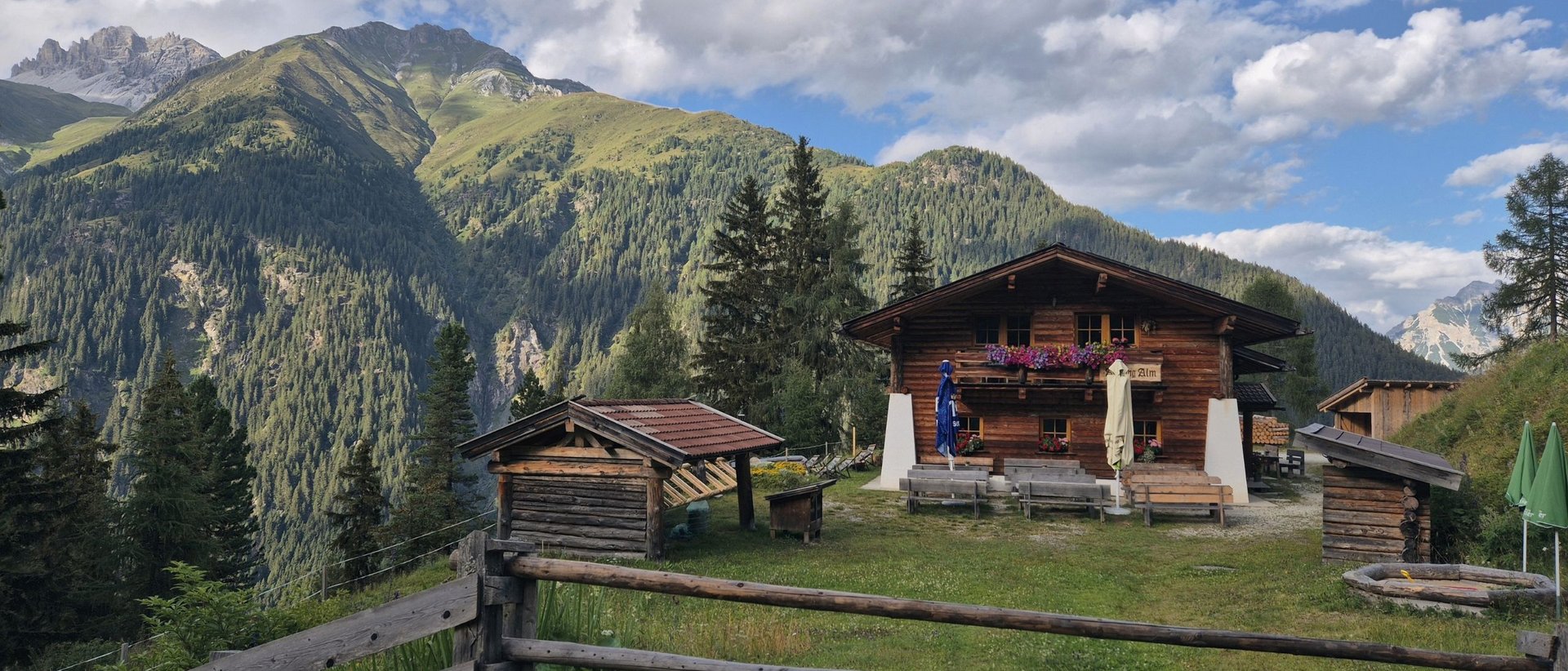 Auffangalm: Unser Tipp für eine gemütliche Wanderung mit Bergpanorama Almhütte mit Holzställen vor bewaldeten Alpenbergen