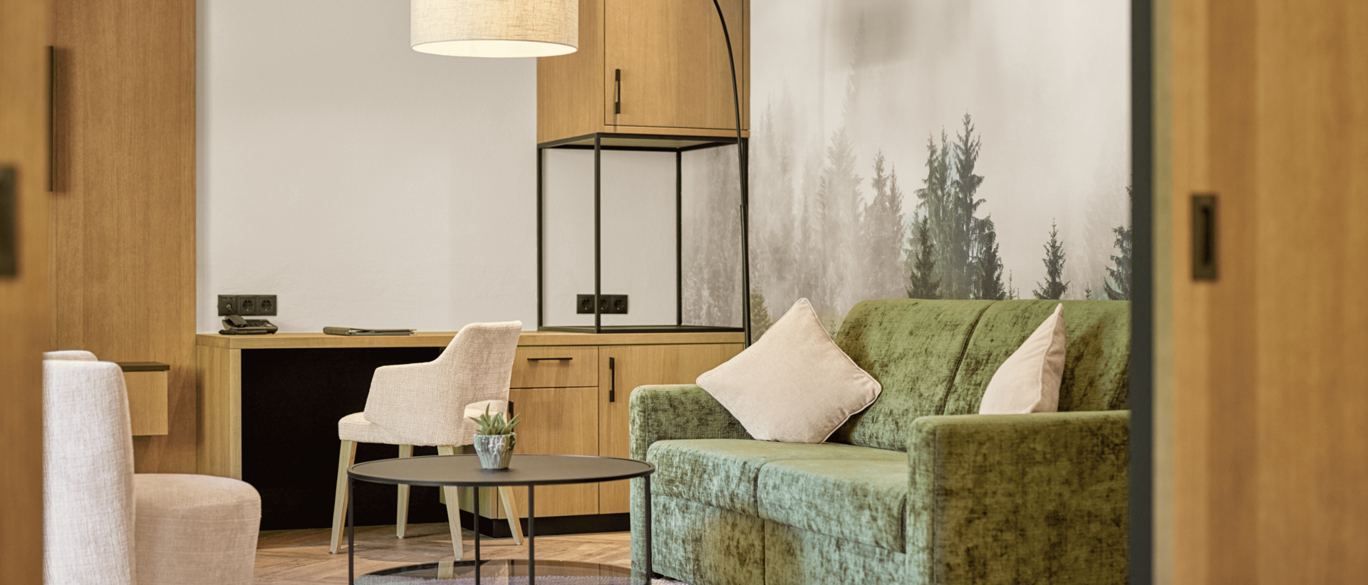 Die perfekte Zimmerkategorie für Ihren Urlaub im Milderer Hof Gemütlicher Wohnbereich mit grünem Sofa, Beistelltisch und Arbeitsbereich