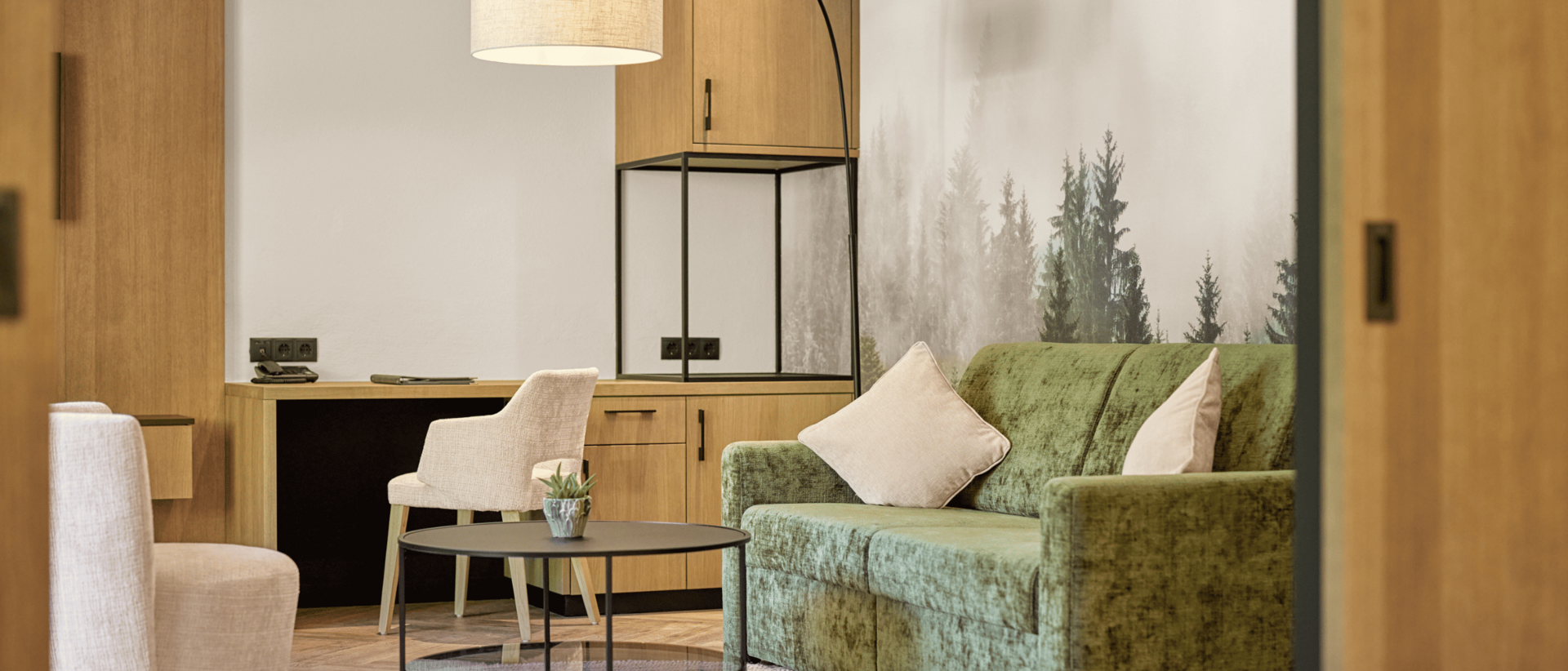 Die perfekte Zimmerkategorie für Ihren Urlaub im Milderer Hof Gemütlicher Wohnbereich mit grünem Sofa, Beistelltisch und Arbeitsbereich