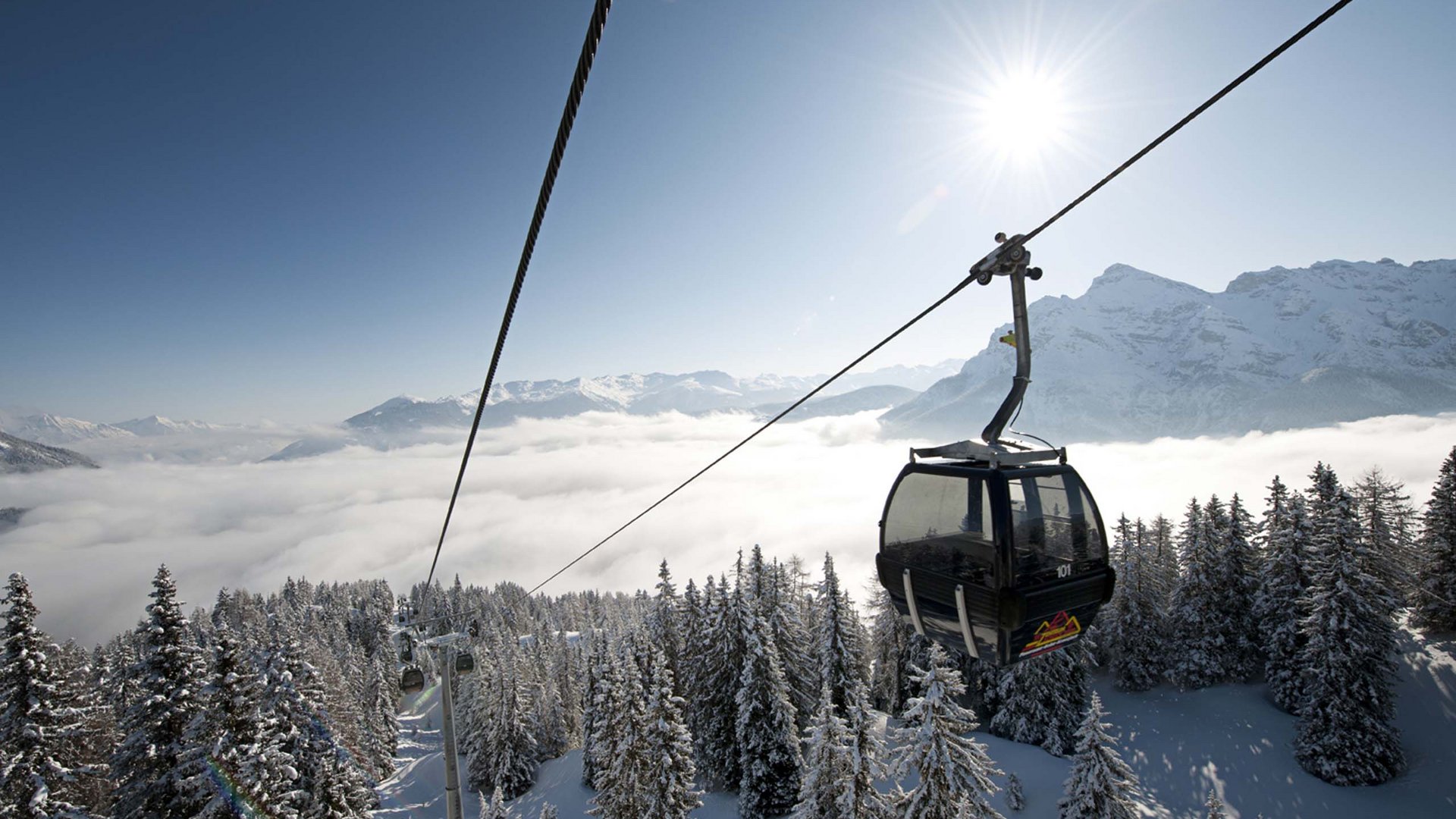 Der Stubaier Gletscher Seilbahn über verschneiten Wald vor Bergpanorama bei sonnigem Himmel