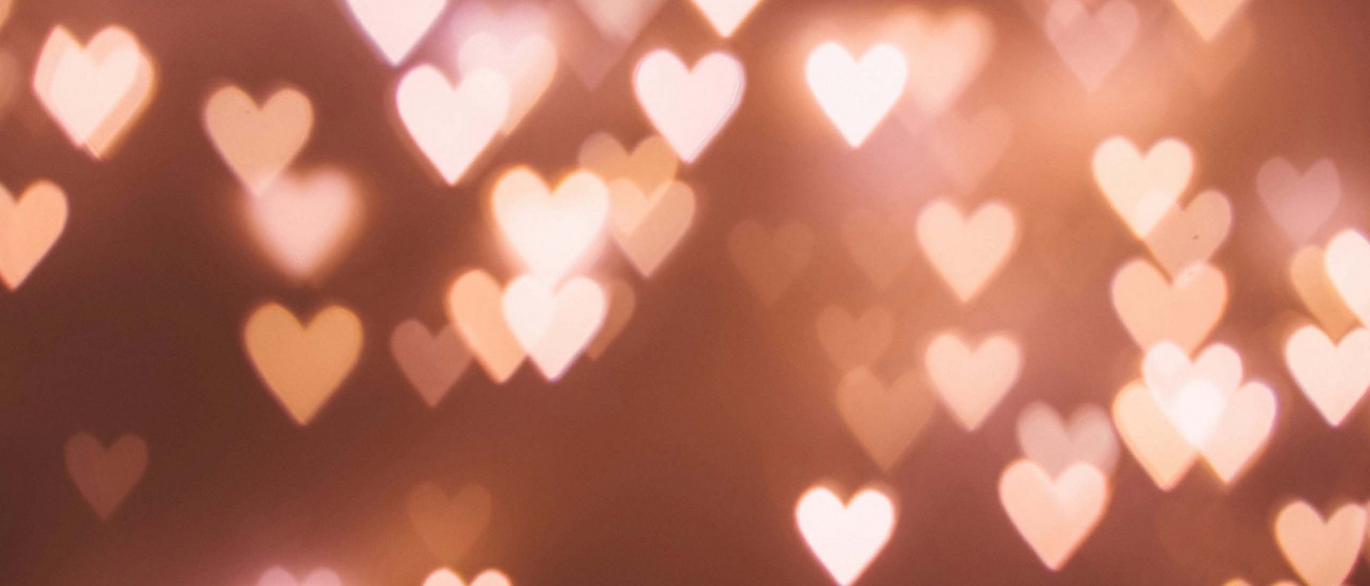 Herzklopfmomente im Milderer Hof Verschwommene Herzlichter auf warmem braunem Hintergrund