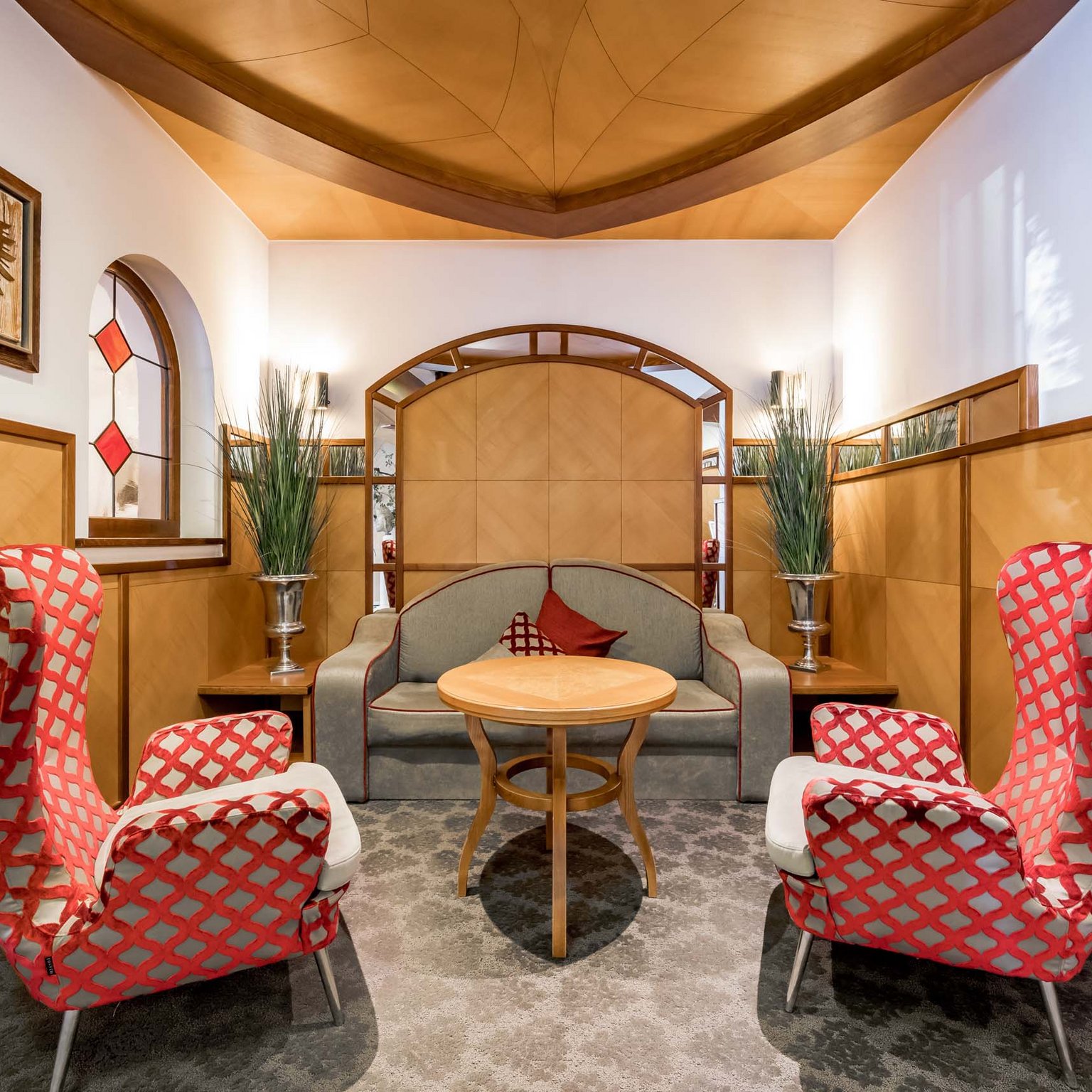 Un hotel con spa in Tirolo per convegni e seminari Area salotto accogliente con poltrone beige e rosse e tavolo in legno