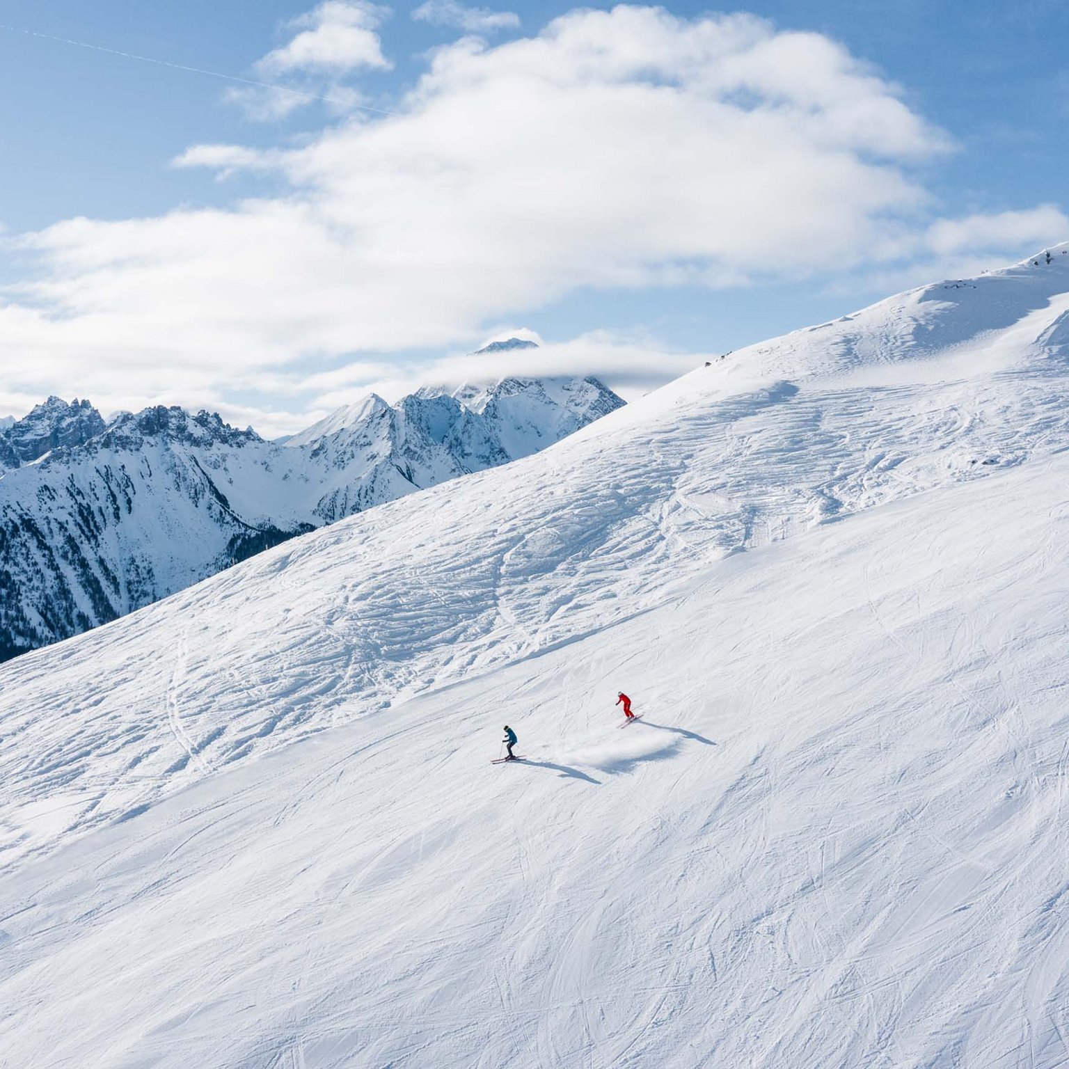 Neustift: the active hotel in Stubaital Two skiers on snowy mountain slope with Alps in the background